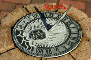 A sundial with a unique design, featuring ornate markings and numerals on its face. The sundial is positioned outdoors, and the shadows cast by the sunlight indicate the time based on the position of the sun in the sky.