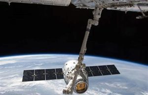 With clouds over Earth forming a backdrop, the SpaceX Dragon commercial cargo craft is grappled by the Canadarm2 robotic arm at the International Space Station. Dragon is scheduled to spend about a week docked with the station before returning to Earth for retrieval.