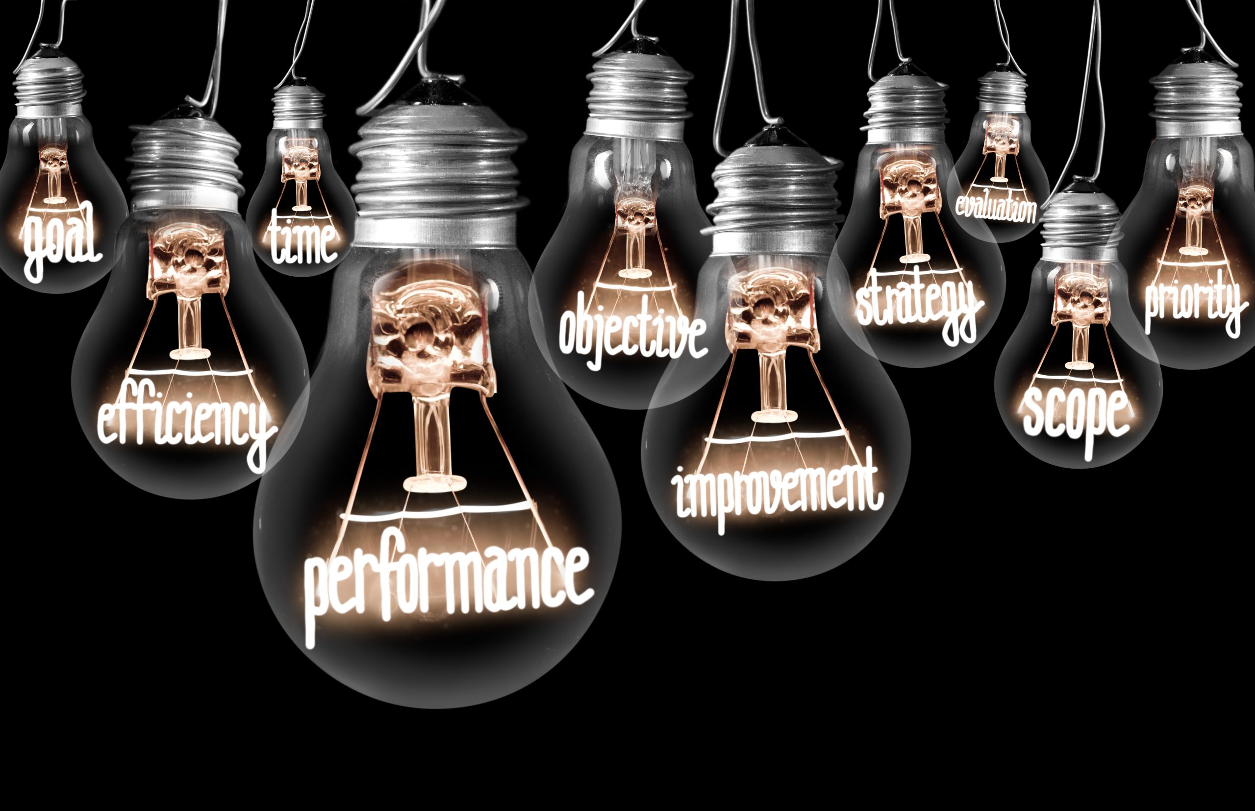 Photo of light bulbs with shining fibers in shapes of PERFORMANCE concept related words isolated on black background