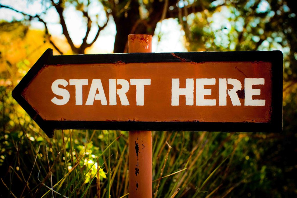 a photo of an arrow-shaped sign reading "Start Here"