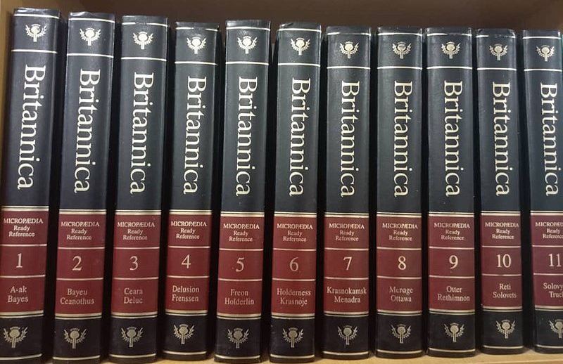 a row of eleven hardbound Encyclopedia Britannica volumes on a shelf