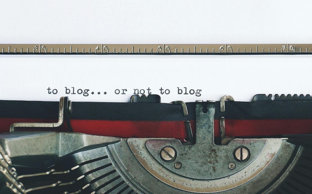 photo of a paper in a typewriter with the words "to blog ... or not to blog" typed