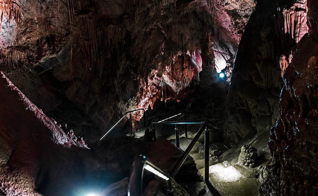 photo shows a slippery concrete staircase descending into a deep dark cave below with dripping stalactites along the walls