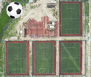 A photograph of a football superimposed on 4 football pitches seen from the air.